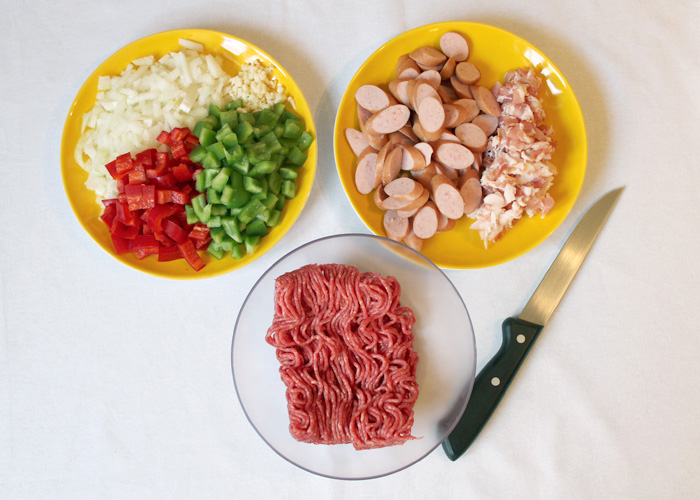 Klein geschnittene Zutaten (Paprika, Zwiebel, Knoblauch, Würstchen, Speck) für philippinische Spaghetti.