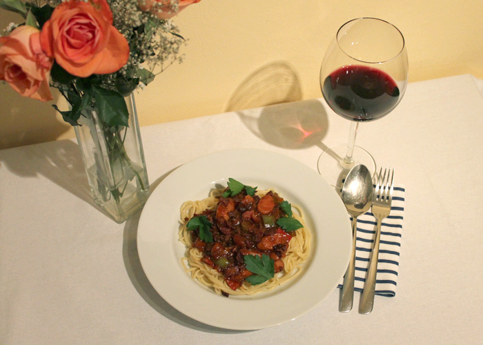 Spaghetti Philippinische Spaghetti auf einem Teller mit Rotwein und Rosen.philippinische Art.